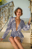 Azure Cotton Dress - Punta Loca A modern twist on a classic, this mini dress encapsulates style with its sleek silhouette. The halterneck design, defined by a plunging V-neck, exudes bold sophistication. Sharply tailored, it features long sleeves that add a touch of refinement, making it a statement piece for any ensemble.