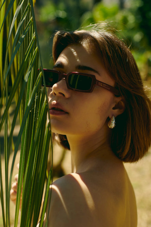Woman wearing Singularidad burgundy Italian sunglasses outdoors — Punta Loca eyewear